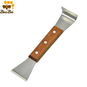Handheld stainless steel hive scraper with a smooth wooden handle being used to clean propolis off a wooden Langstroth beehive box